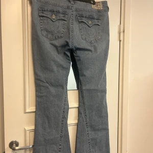 True Religion ljusblå bootcut jeans - Hej! Säljer dessa jeans från true religion, eftersom att de är för stora för mig. Jeansen är i storlek 32.  Byxorna köptes i oktober och har använts sparsamt. Byxorna har inga tydliga defekter som syns, däremot så är slutet av byxorna lite slitna, och det finns även små hål i midjebandet av säkerhetsnålar som ej syns. Skriv gärna till mig för mer info och bilder. 🤗