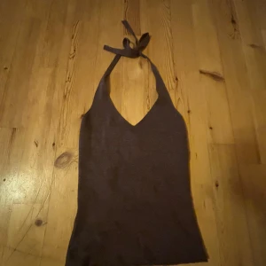 Brun ribbad halterneck-topp från BikBok - Säljer en brun ribbad halterneck-topp från BikBok. Toppen har v-ringning och knyts i nacken. Perfekt för varma dagar och enkel att matcha med olika outfits.