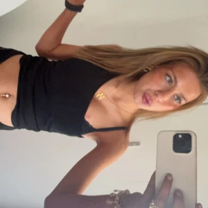 Svart croppad linnetopp - Säljer en svart croppad linnetopp med smala axelband. Toppen har en enkel och stilren design som passar perfekt till jeans eller kjol. Perfekt för varma dagar eller lager-på-lager.