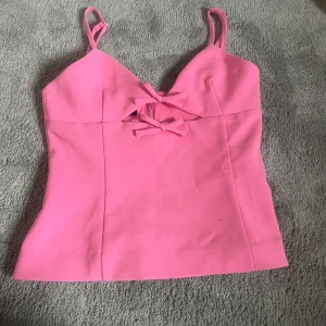 Rosa topp med rosetter från Zara - Säljer en rosa topp från Zara med rosetter på. Toppen har dragkedja i ryggen och har inga defekter 