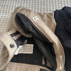 Beige chinos från Jack & Jones Slim Marco - 3 stycken Snygga beige chinos från Jack & Jones, modell Slim Marco. Byxorna har slim passform, klassisk design med knapp och dragkedja i midjan samt svarta innerdetaljer. Perfekta för en stilren look.