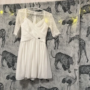 Vit studentklänning/skolavslutning - Superfin vit klänning från Chiara Forthi med spets upptill och omlottdesign framtill. Klänningen har trekvartsärm i spets och en lätt utställd kjol. Perfekt för sommarens tillfällen! Perfekt till student!!😍😍använd en gång. Storlek står ej men bedömer att den är strl S/M enligt att den passade mig när jag hade M men även när jag hade S.