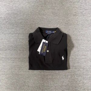 Svart pikétröja från Polo Ralph Lauren - En klassisk polo ralph lauren pike i svart, väldigt stilren och passar perfekt till sommarn, säljs pågrund av att den var för liten 