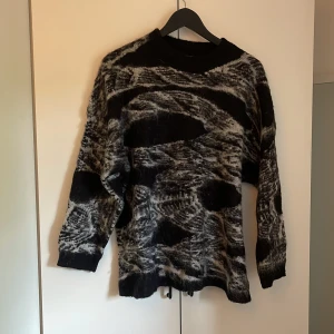 Svart och grå mönstrad stickad tröja från Golden Days - Säljer en stickad tröja från Golden Days i svart och grått med abstrakt mönster. Tröjan har lång ärm och rund halsringning. 