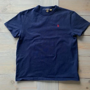 T-shirt från Polo Ralph Lauren - Klassisk mörkblå t-shirt från Polo Ralph Lauren i storlek M. Bra skick, använd ett fåtal gånger. 