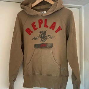 Brun/Beige hoodie från Replay - Säljer en unik vintage beige/ brun hoodie från Replay med röd broderad text och tryck framtill. Jättefint skick, ända defekten är att den inte har några snören i luvan (sista bild).  Skriv för fler bilder/ frågor.🫶