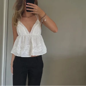 Vit topp från Zara - Säljer en vit söt linnetopp från Zara med tunna axelband och v-ringning som jag inte har använt. Toppen har broderade detaljer och spets längs kanterna samt en luftig, lätt utsvängd passform. Perfekt för varma sommardagar!💗💗 De första två bilderna är från tjejen jag köpte den av och den sista är min bild