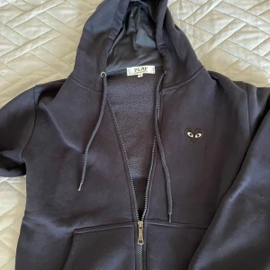 Svart hoodie från Comme des Garçons Play - Mörkblå hoodie med dragkedja från Comme des Garçons Play. Jätte skön tröja  fin till sommaren den är bekväm att ha på sig storlek M