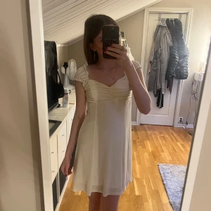 Vit crinkle mini klänning från Gina Tricot - Supersöt vit kortklänning från Gina Tricot i crinkle-material. Klänningen har rynkade detaljer vid bysten och axelband. Perfekt för sommarens alla tillfällen! Aldrig använd!