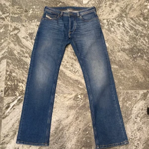 Blå Diesel Larkee jeans - Klassiska blå jeans från Diesel, modell Larkee. Byxorna har raka ben, fem fickor och tydliga sömmar. Märkespatch bak i midjan och diskreta slitningar framtill. Perfekta för en avslappnad stil. Felköp då de blev för långa så i princip oanvända. 