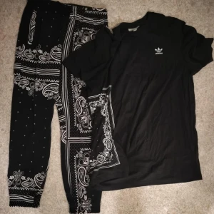 Svart t-shirt o byxor från Adidas  - Svart t-shirt o byxor från Adidas med liten vit logga på bröstet. T-shirten har klassisk passform och rund halsringning. Perfekt för en sportig och avslappnad stil.