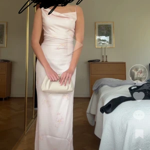 Ljusrosa långklänning med blommigt mönster - Säljer en elegant ljusrosa långklänning med diskret blommigt mönster. Passar mig som är 171 cm. Prislapp kvar! Använd gärna köp nu