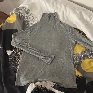 Grå polotröja från 157 - Säljer en enkel och stilren grå polotröja från 157. Tröjan har lång ärm och är tillverkad i ett mjukt och tunt bomullsmaterial. Perfekt att bära som lager eller för en clean look.