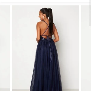 Balklänning - Super fin blå balklänning som får ett fint fall på kroppen. Använd en gång på min killes bal. Öppen rygg med knytning. Säljer för 500. Priset är inte satt i sten.