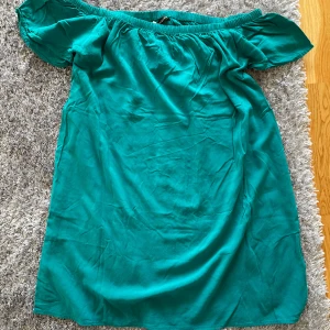 Turkos offshoulder klänning. S - Säljer en snygg turkos offshoulder klänning i hållbar viskos. Perfekt för varma dagar med sin luftiga design och korta ärmar. Klänningen har en elastisk överdel som ger en bekväm passform. Passar perfekt för sommarens alla tillfällen! Kostade 400 kr
