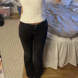 Svarta bootcut jeans - Snygga svarta bootcut jeans med lågmidja. De har en klassisk femficksdesign och stängs med knapp och dragkedja. Perfekta för en stilren look.❤️❤️svart/mörkgråa