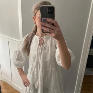Vit klänning med knytband - Charmig vit klänning med knytband framtill och trekvartsärmar. Klänningen har en luftig passform och fina detaljer som ger en romantisk känsla.köptes från vero Moda för 300kr,prislapp finns kvar då jag bara har testa den!!❤️