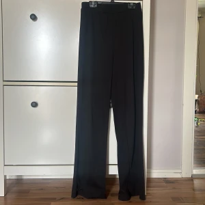 Svarta vida byxor - Snygga svarta vida byxor med diskret randigt mönster. Perfekta för en stilren look. Byxorna har en hög midja och är tillverkade i ett mjukt material som ger en bekväm passform.