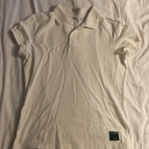 Vit pikétröja från Björn Borg - Säljer en stilren vit pikétröja från Björn Borg. Tröjan har en klassisk krage med knappar och korta ärmar. Perfekt för en avslappnad men ändå snygg look. Passar bra till både jeans och shorts.