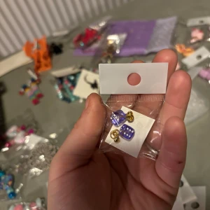 Lila prickiga örhängen - Säljer ett par söta lila örhängen med vita prickar. De har en fyrkantig form och guldiga detaljer. Perfekta för att lägga till en färgglad touch till din outfit!