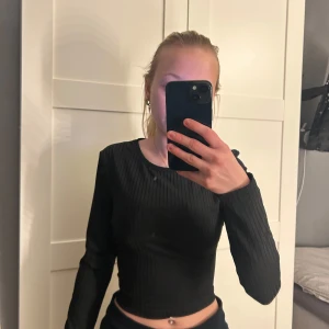 Svart ribbad topp från NA-KD - Snygg svart ribbad topp från NA-KD med öppen rygg och snörning. Perfekt för en stilren look. Långärmad design som passar bra till olika outfits. Aldrig använd!💞