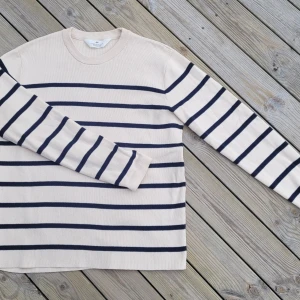 Beige och marinblå randig tröja från H&M - Säljer en stilren beige tröja med marinblå ränder från H&M. Tröjan har långa ärmar och en rund halsringning, perfekt för en avslappnad look. Passar bra till både jeans och chinos.
