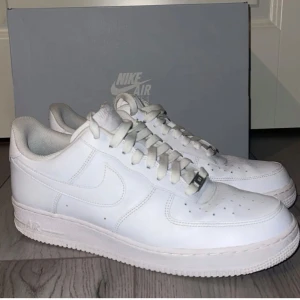 Vita Nike Air Force sneakers - Klassiska vita Nike Air Force sneakers med snörning. Perfekta för en stilren look och bekväma att bära hela dagen. En tidlös modell som passar till det mesta.