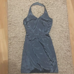 figursydd halterneck klänning - Klänningen är uppsydd för ca S i Thaildand, endast använd en gång.                                  Elegant mörkblå halterneckklänning i satin med en smickrande passform. Klänningen har en stilren design med en v-ringad hals och knäppning i nacken. Perfekt för speciella tillfällen.
