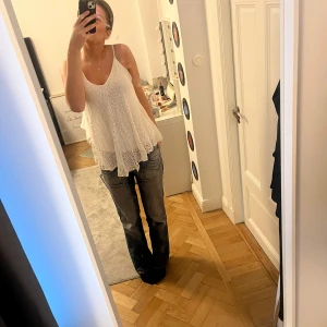 Vit spetslinne - Säljer ett luftigt vitt spetslinne med smala axelband. Toppen har en lös passform och volangdetaljer som ger en romantisk känsla. Perfekt för varma sommardagar.