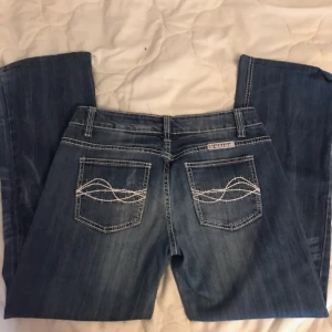 Blå jeans från Cowgirl Tuff Co. - Snygga blå jeans från Cowgirl Tuff Co. med dekorativa sömmar på bakfickorna. De har en klassisk femficksdesign och en knappgylf. Perfekta för en avslappnad stil. Säljer då jag inte använder dessa😊 innerben:72cm midjemått:37cm