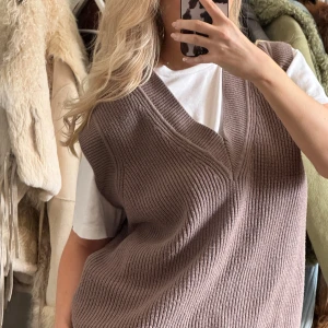 Brun stickad väst från Zara - Säljer en snygg brun stickad väst från Zara. Västen har en v-ringad design och en bekväm passform som är perfekt för lager-på-lager. Den är ribbad vid kanterna vilket ger en stilren look. Oversized.
