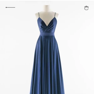 Marinblå ballklänning med open back - Elegant marinblå ballklänning i satin med smala axelband och v-ringad design. Klänningen har en öppen rygg och ett knytband i midjan för en smickrande passform. Köpt i Italien från butiken Ateljé Eme. Fråga efter fler bilder!!