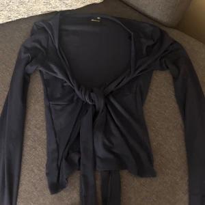 Mörkblå knytkofta från Gina Tricot - Säljer denna fina tröja Gina Tricot. Den har långa ärmar och en stilren knytning framtill. Passar bra till både vardag och speciella tillfällen. Säljer den då den inte kommer till användning, den är aldrig använd så den är helt ny!🩷