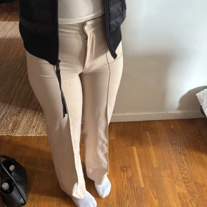 Beige byxor med dragkedja - Snygga beige byxor med dragkedja framtill. De har en hög midja och en rak passform som ger en stilren look. Perfekta för en avslappnad men ändå chic stil.