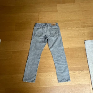 Grå jeansbyxor Loose/Chris - Säljer ett par grå jeansbyxor i modellen Loose/Chris. Byxorna har en lös passform och klassisk femficksdesign. Perfekta för en avslappnad stil.