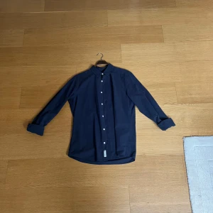 Mörkblå skjorta från Only & Sons - Snygg mörkblå skjorta från Only & Sons i slim fit. Skjortan har långa ärmar och knappar framtill. Perfekt för en stilren look.