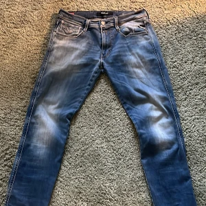 Hyperflex jeans Replay - Snygga blå jeans från Replay med Hyperflex-teknologi för extra komfort och stretch. De har en klassisk femficksdesign och en diskret broderad detalj på bakfickorna. Perfekta för en stilren look. Replay anbass. W32 passar som W31, L32