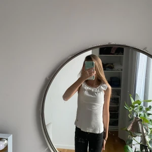 Super snygg vit topp med volangdetalj.  - Säljer en söt vit topp med volangdetalj runt halsen. Perfekt för sommardagar och kan enkelt matchas med olika outfits. Den är i storlek 130 men funkar även för större storlekar. Inga fläckar. Inga hål. Bra skick. 