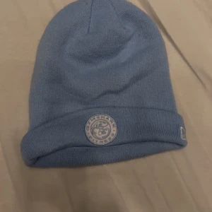 Gymshark mössa - Snygg blå stickad mössa med en broderad logga framtill. Perfekt för kyliga dagar och ger en stilren look. Passar både till vardags och mer avslappnade tillfällen. Inga defekter