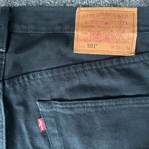 Svarta Levi's 501 jeans - Säljer ett par klassiska svarta Levi's 501 jeans. De har en rak passform och är tillverkade i slitstarkt denim. Perfekta för en stilren look.