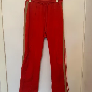 Röda mjukisbyxor från Vero Moda - Snygga röda mjukisbyxor från Aware by Vero Moda med beige sidopanel och vita ränder. Perfekta för en avslappnad stil.