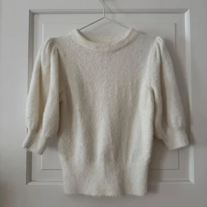 Vit fluffig stickad tröja från H&M - Supermjuk och fluffig krämvit stickad tröja från H&M med puffiga ärmar och ribbad halsringning. Tröjan  är tillverkad i en blandning av polyamid, akryl och elastan. Puffärmar och mudd längst ner. Använd ett fåtal gånger. Storlek XS. Normal i storlek. Passar storlek XS-M beroende på hur man vill att den ska sitta då den är stretchig. Jag har vanligtvis storlek M. 
