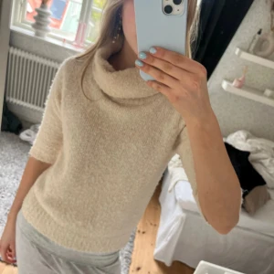 Beige stickad polotröja - Mysig beige stickad polotröja med kortare ärmar och lös polokrage. Nästan helt oanvänd och passar till både jeans och kjol. Supermjuk och fluffig känsla i materialet. Nypris 300kr