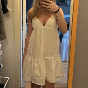 Vit ärmlös kortklänning med v-ringning - Säljer en söt vit kortklänning med djup v-ringning och volang nertill. Använd 2 gånger