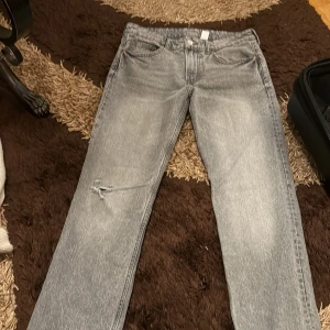 Grå straight jeans med slitning - Säljer mina mid waist raka gråa jeans som har ett par som har slit på bennen men dom är bara använda ett fåtal gånger samt är i nyskick och deras model med flera slit är så från H&m. Köpt för 400kr säljer för 150kr.