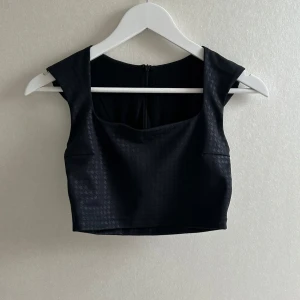 Svart croppad topp från Aim'n - Snygg svart croppad topp från Aim'n med diskret mönster och breda axelband. Toppen har en tight passform och dragkedja bak. Använd fåtal gånger💗💗