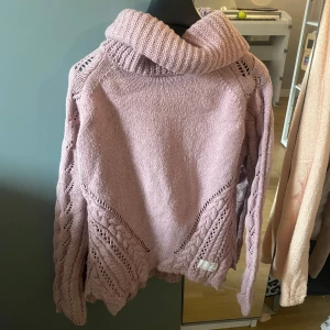 Ljuslila stickad polotröja från Odd Molly - Superfin ljuslila stickad polotröja från Odd Molly med bred polokrage och snygga flätade detaljer. Tröjan har lång ärm och ett vackert mönster både fram och bak. Perfekt för dig som vill ha något både mysigt och stilrent.