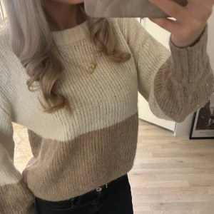 Beige och vit stickad tröja från Lindex - Säljer en mysig stickad tröja från Lindex i storlek S. Tröjan har breda blockränder i beige och vitt, rund halsringning och långa ärmar. Perfekt för en avslappnad och stilren look.