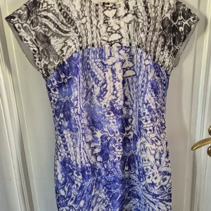 Mönstrad klänning från Armani Exchange - Säljer en snygg klänning från Armani Exchange med svartvitt mönster upptill och blått abstrakt mönster nedtill. Jättebra skick💕