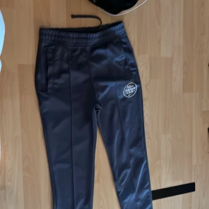 Mörkblå träningsbyxor från Nike - Snygga mörkblå träningsbyxor från Nike med resår i midjan och dragsko. Byxorna har en vit Nike-logga på låret och raka ben. Perfekta för träning eller chill.